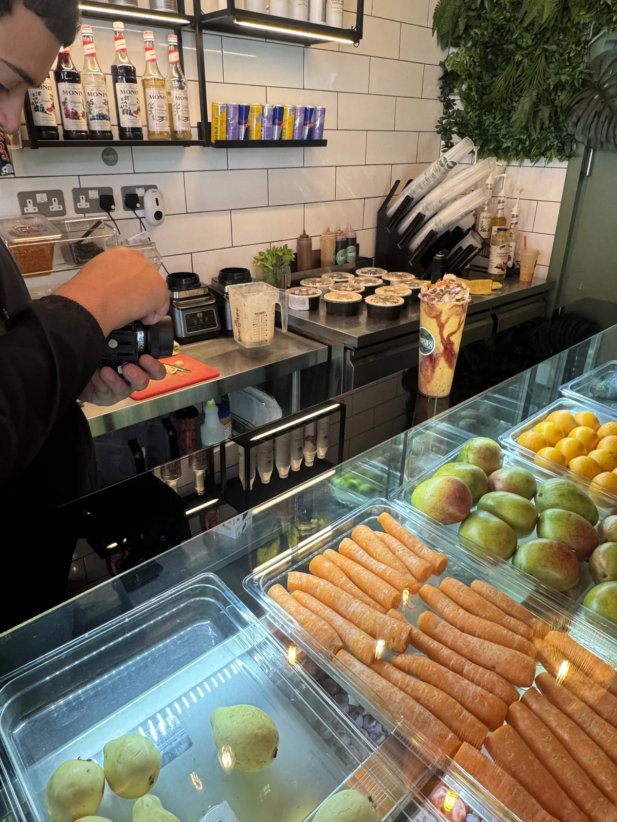 A camera operator photographing a Habibi Juice drink at the counter.