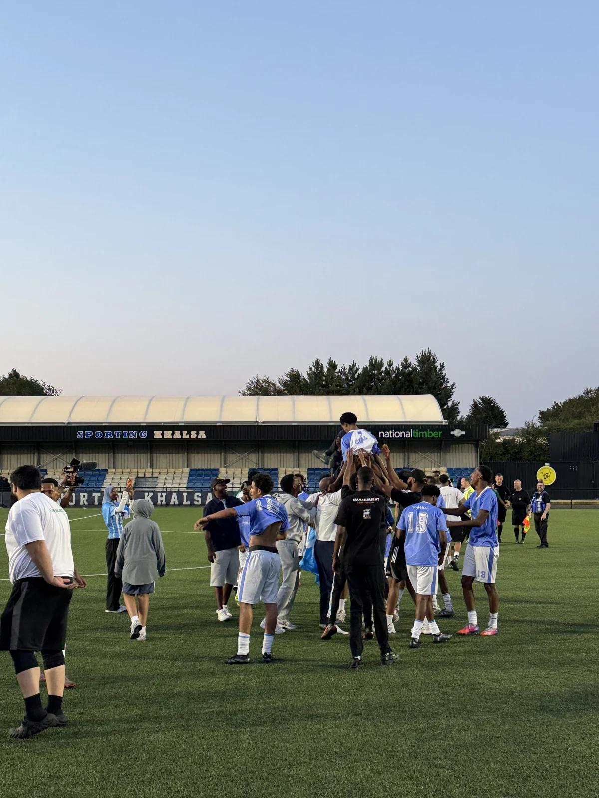 Unity Cup players celebrating together on the pitch after the match.
