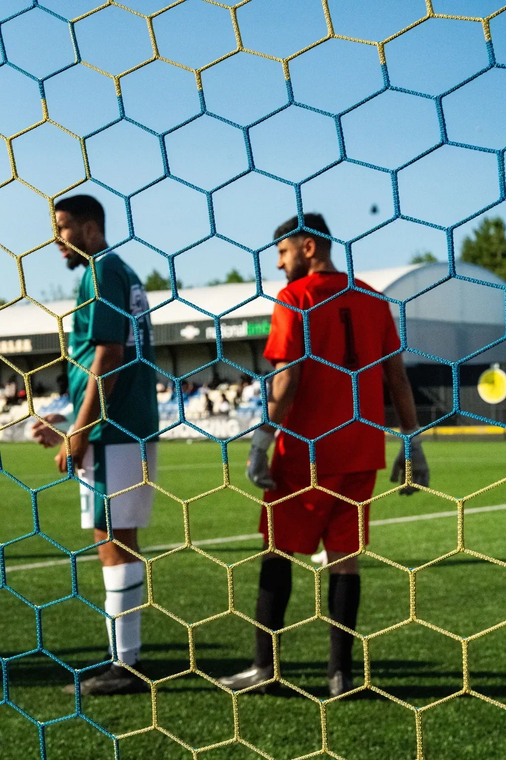 Unity Cup match action framed through the goal net with several players in view.